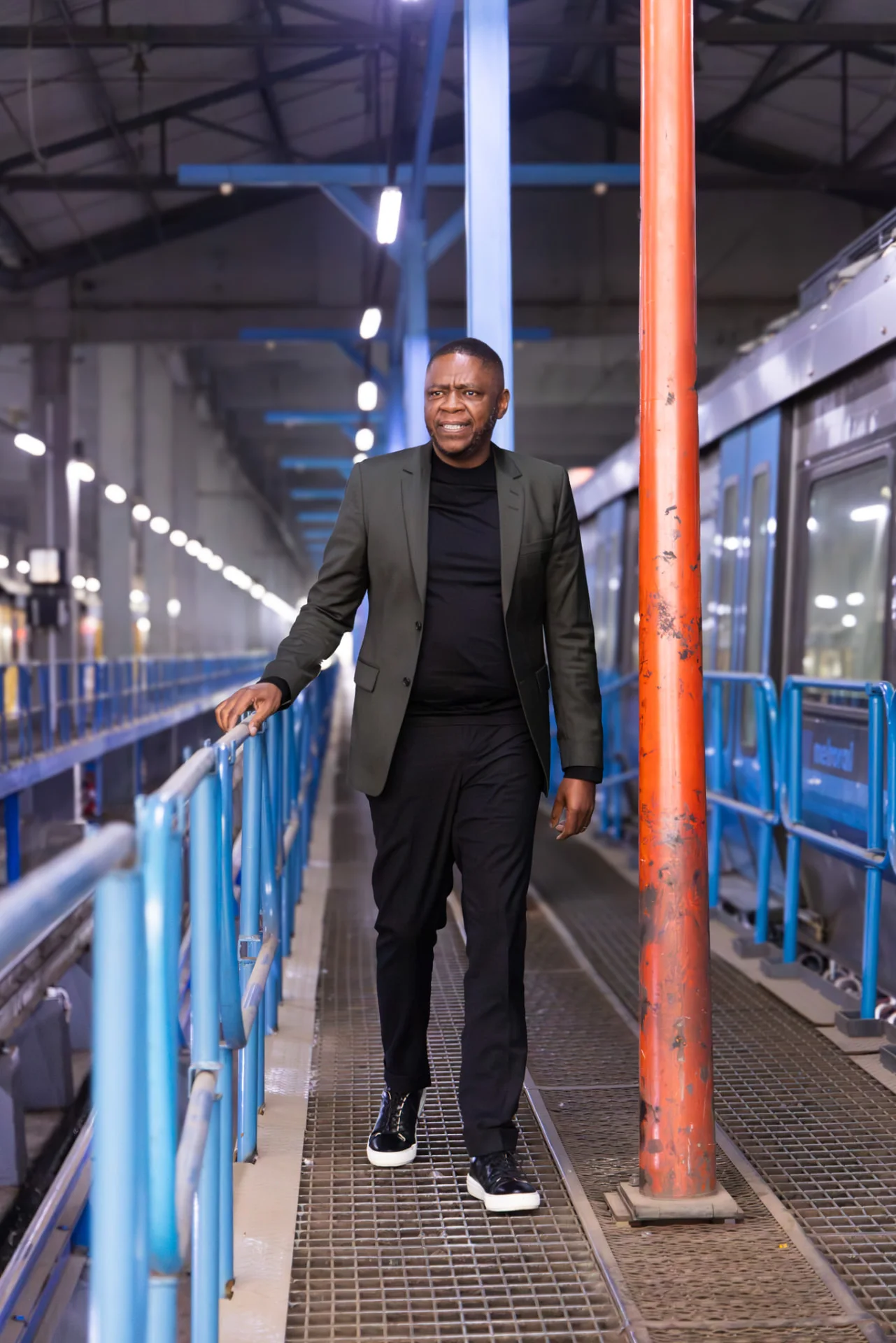 Mr Themba Mosai walking along a maintenance walkway inside a train depot.