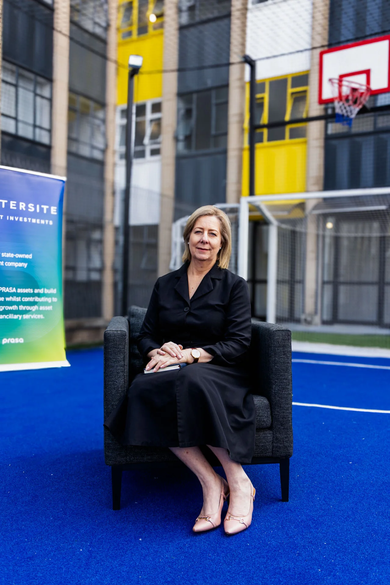 Ms Annette Lindeque seated on the rooftop court beside an Intersite banner.
