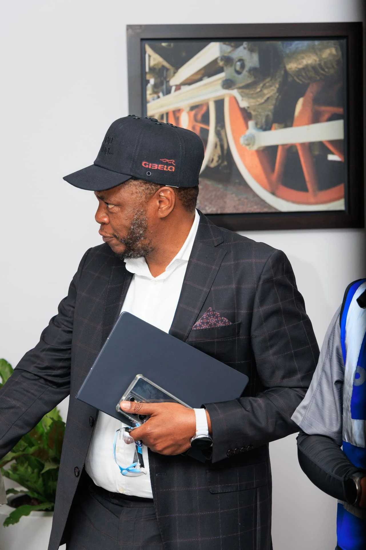 An attendee in a checked suit and branded cap, photographed looking to the side.