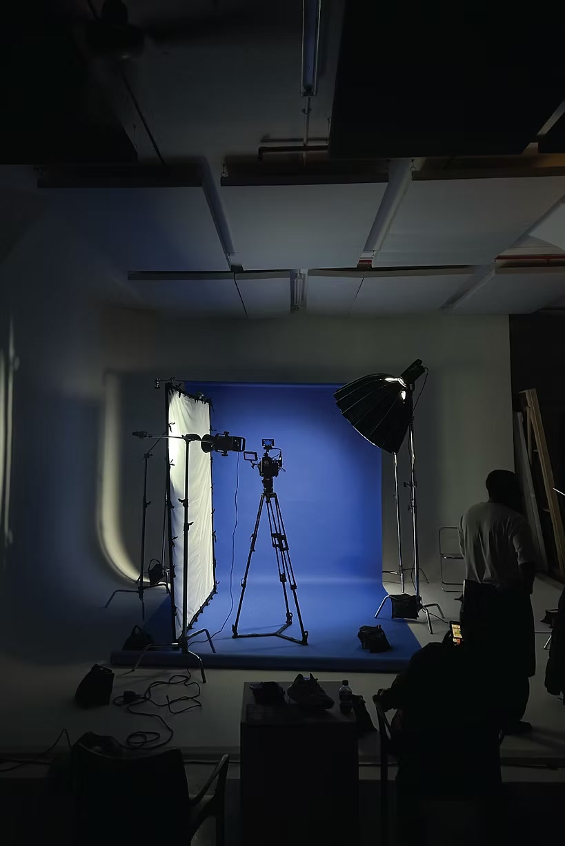 Tales Of The Cool shoot studio set with a blue backdrop, a camera on a tripod and lighting in place