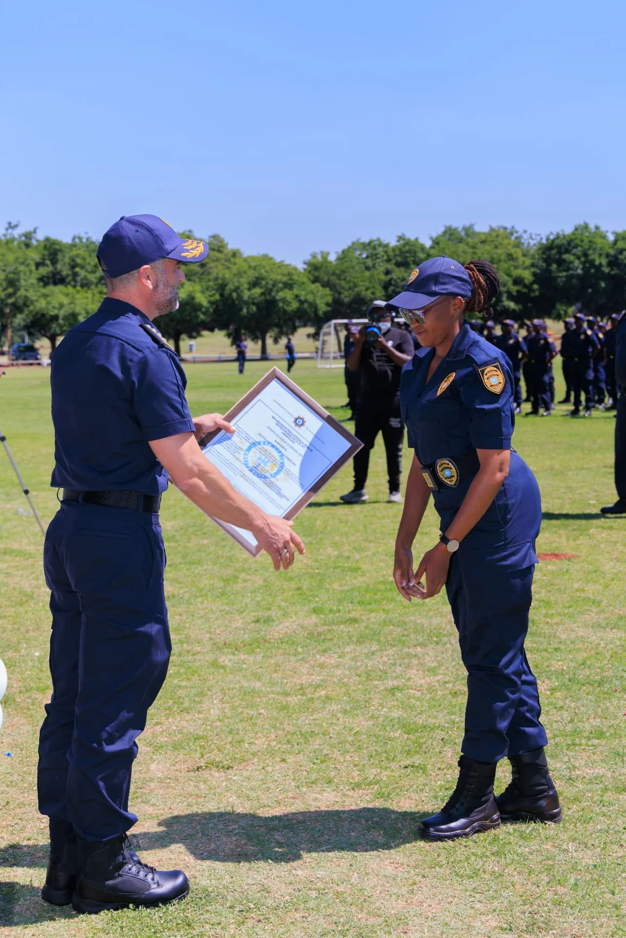 An officer presenting a framed certificate to a uniformed participant.