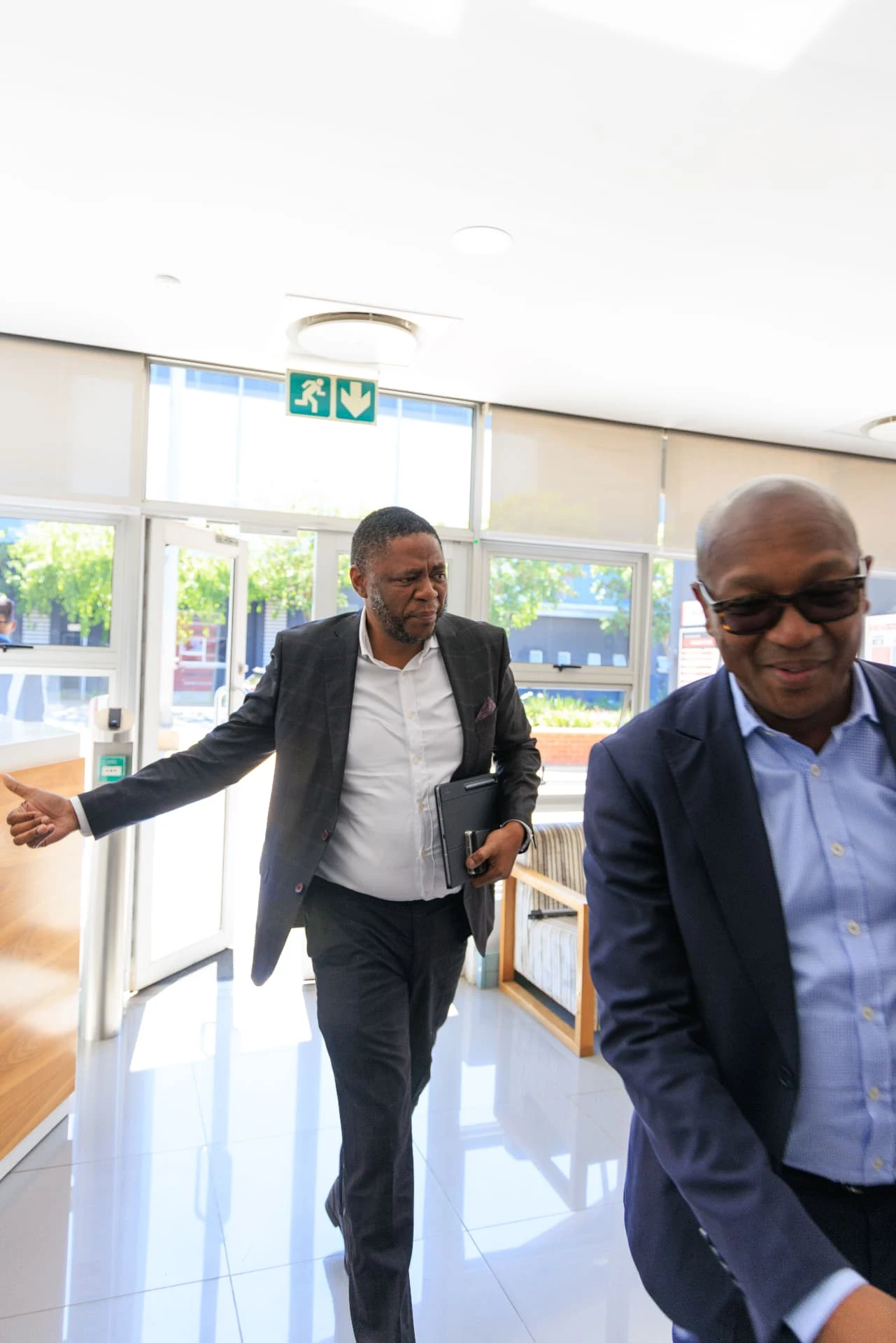 Two attendees moving through a bright entrance area.